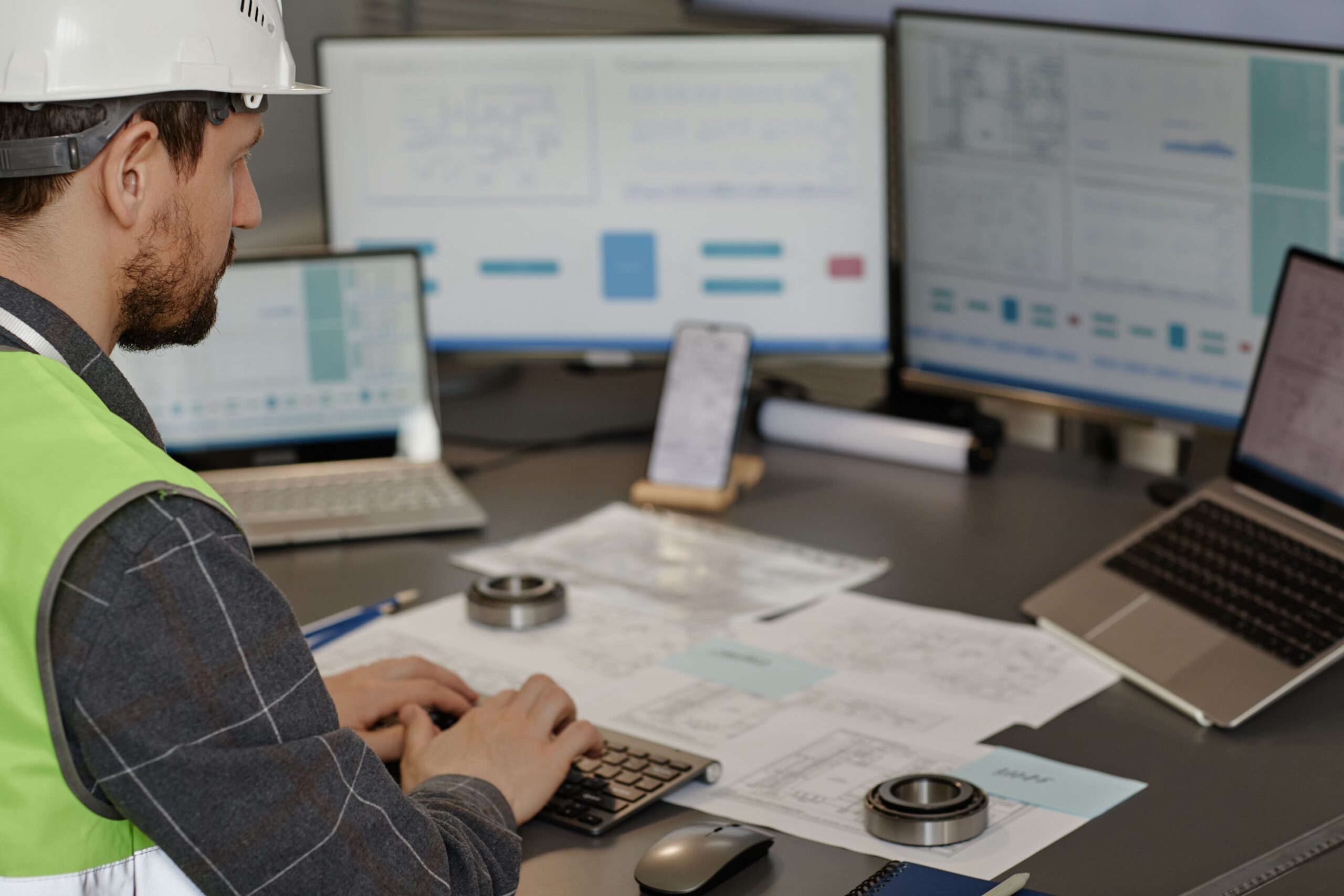 side-view-male-engineer-wearing-hardhat-workplace-office-using-computer-designing-blueprints-copy-space